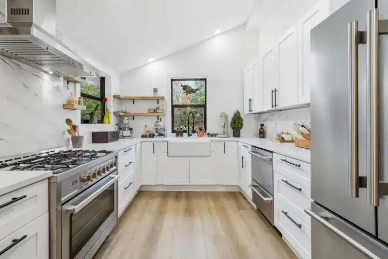 White kitchen at 356 Hyde Road with stainless steel appliances, wood-look floors, and open shelving