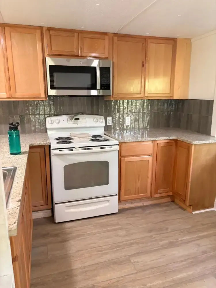 Warm wood kitchen cabinets, range, microwave, and tiled backsplash at 495 Pack Road in Ranger
