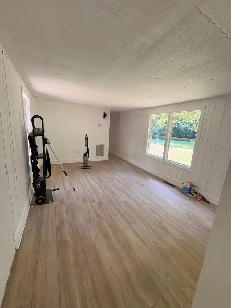Spacious living room with paneled walls, wood-look flooring, and large windows at 495 Pack Road in Ranger