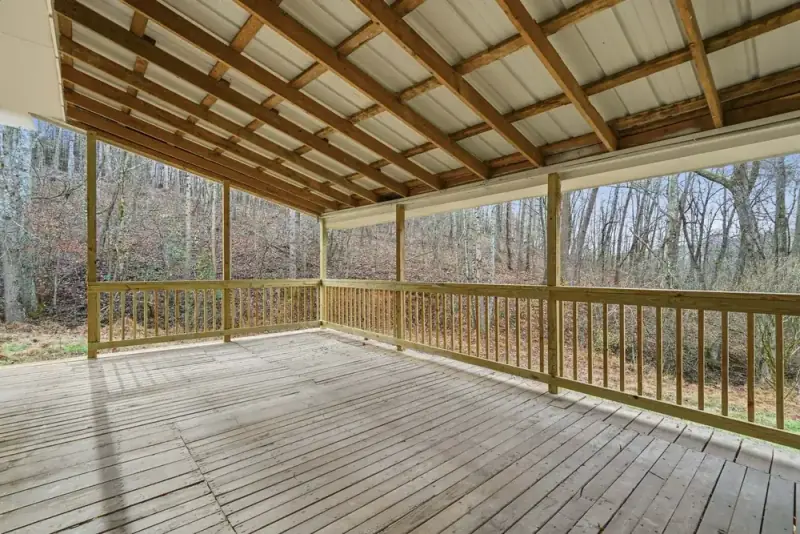 Covered wood deck surrounded by trees at 6757 Henderson Mtn